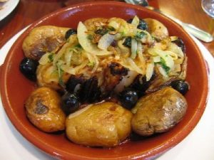 a bowl of code fish with onions, olives and potatoes