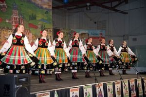 8 girls in Polish cultural dresses on a stage