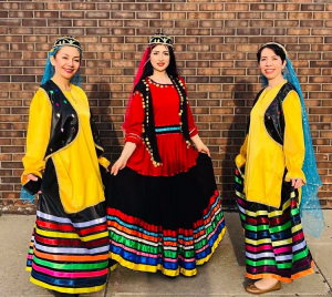 3 ladies posing in front of a brick wall in traditional attire